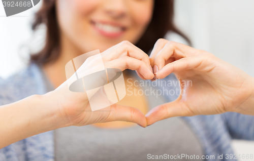 Image of close up of happy woman showing heart with hands