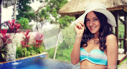 Image of happy young woman in bikini swimsuit and sun hat