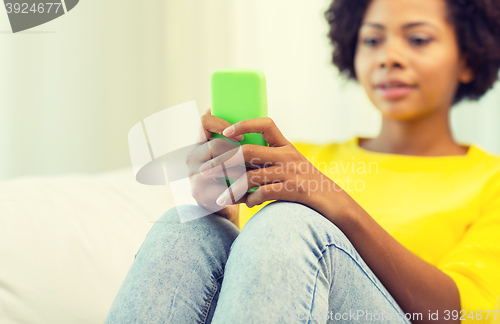 Image of happy african woman with smartphone at home