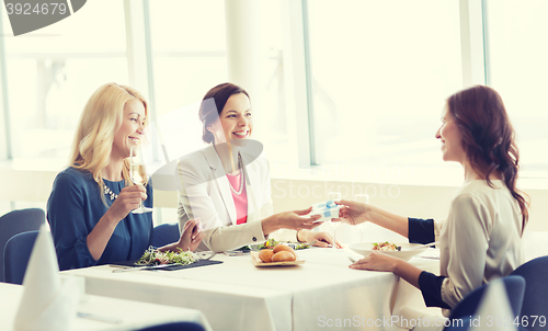 Image of happy women giving birthday present at restaurant