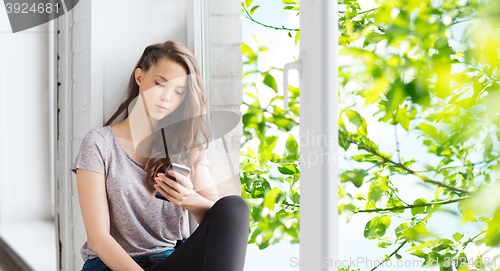 Image of sad pretty teenage girl with smartphone texting