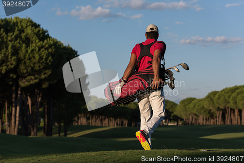 Image of golfer  walking and carrying golf  bag