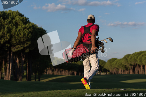 Image of golfer  walking and carrying golf  bag