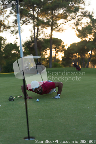 Image of golf player blowing ball in hole with sunset in background