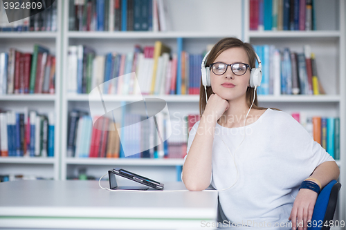 Image of female student study in library, using tablet and searching for 