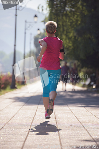Image of sporty woman running  on sidewalk