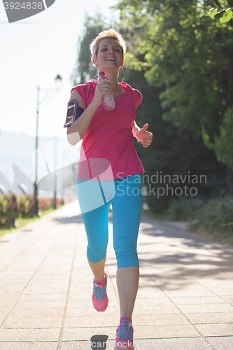 Image of sporty woman running  on sidewalk