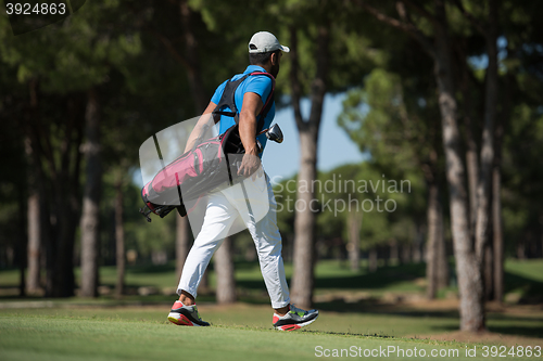 Image of golf player walking and carrying bag