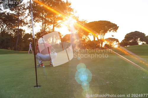 Image of golf player aiming perfect  shot on beautiful sunset