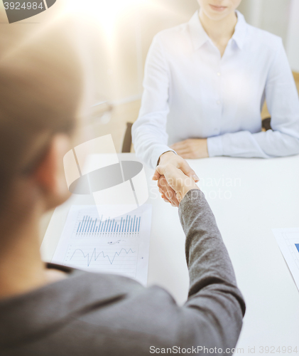 Image of two calm businesswoman shaking hands in office