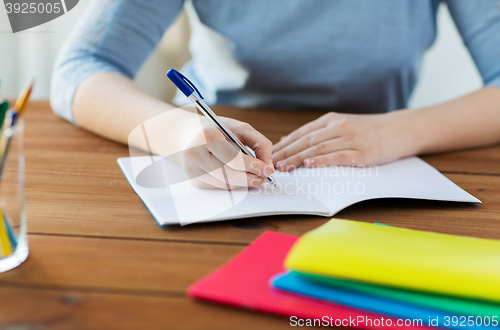 Image of close up of student writing to notebook at home