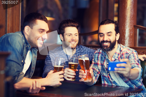 Image of friends taking selfie and drinking beer at bar