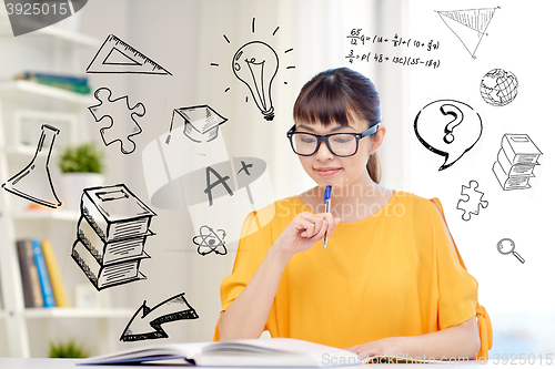 Image of smiling young asian woman reading book at home