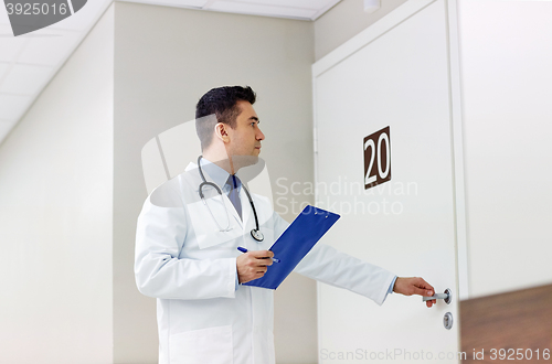 Image of doctor with clipboard opening hospital ward door