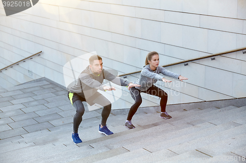 Image of couple doing squats on city street stairs