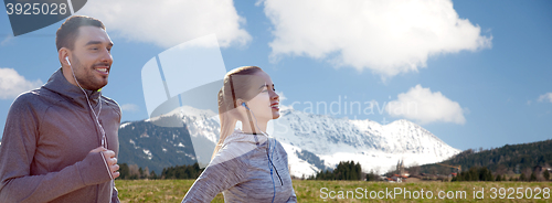 Image of happy couple with earphones running in city