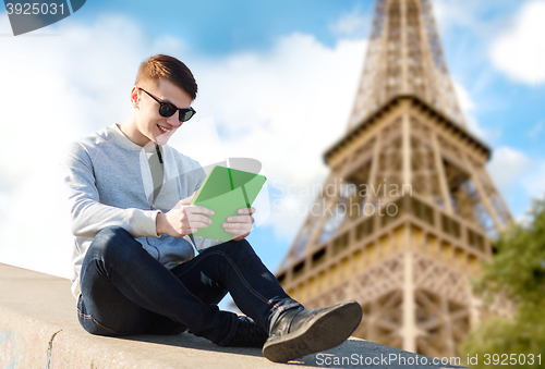 Image of happy young man with tablet pc over eiffel tower