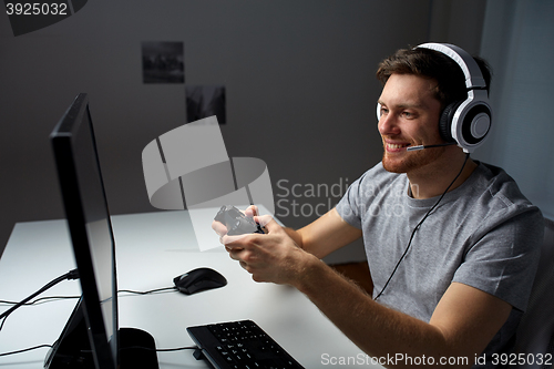 Image of man in headset playing computer video game at home