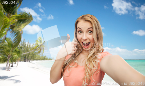 Image of happy woman taking selfie and showing thumbs up