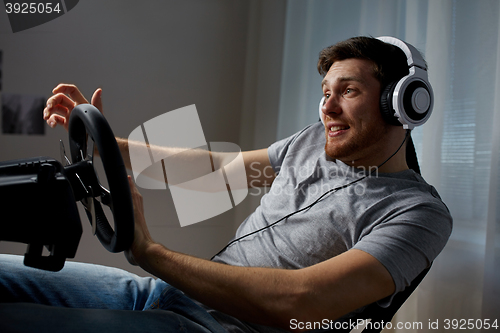Image of man playing car racing video game at home