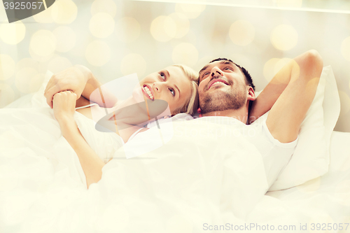 Image of happy couple lying in bed at home