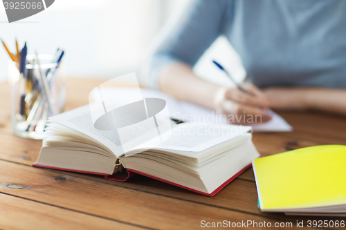 Image of close up of student with book and notebook at home