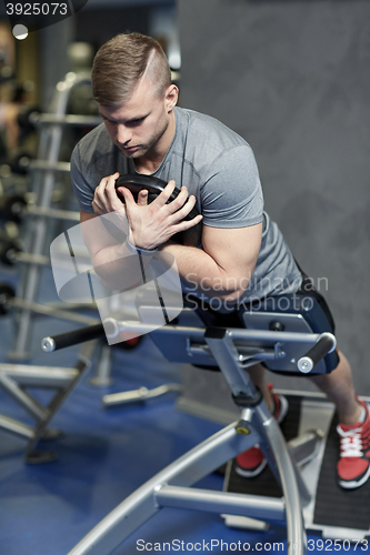 Image of young man flexing back muscles on bench in gym