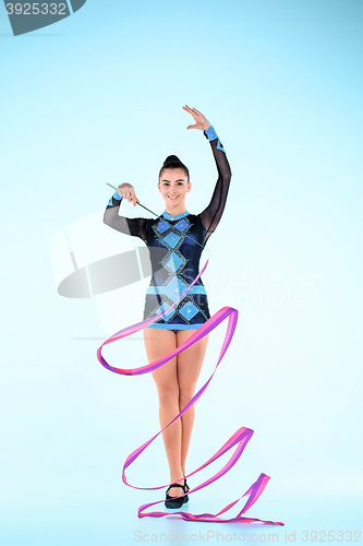 Image of The girl doing gymnastics dance with colored ribbon on a blue background