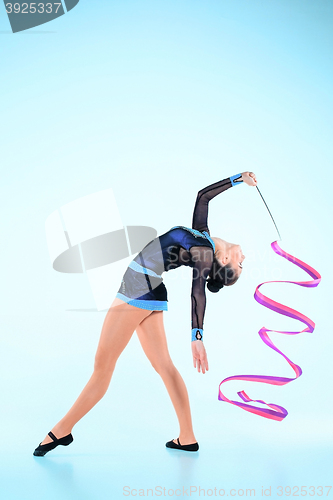 Image of The girl doing gymnastics dance with colored ribbon on a blue background