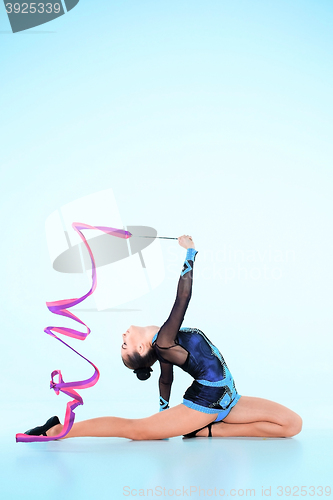 Image of The girl doing gymnastics dance with colored ribbon on a blue background