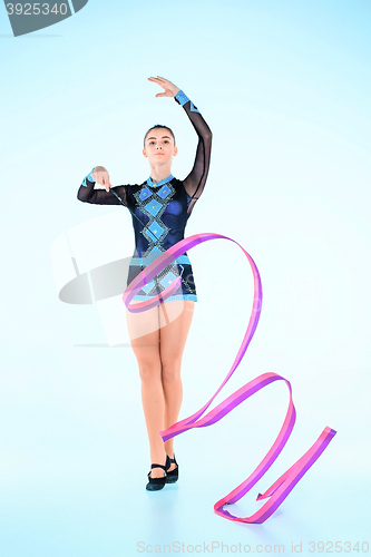 Image of The girl doing gymnastics dance with colored ribbon on a blue background