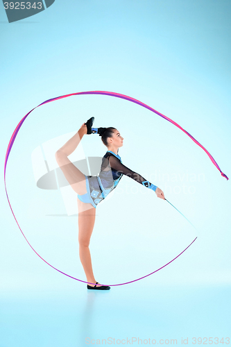 Image of The girl doing gymnastics dance with colored ribbon on a blue background