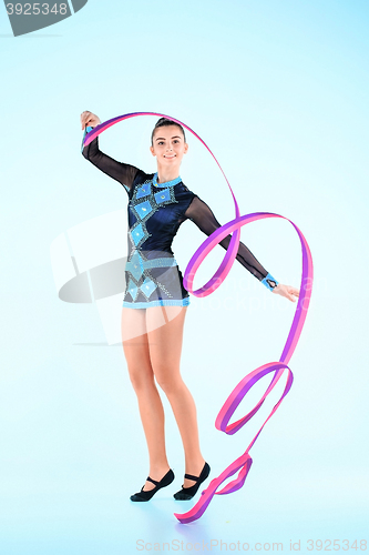 Image of The girl doing gymnastics dance with colored ribbon on a blue background