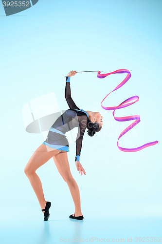 Image of The girl doing gymnastics dance with colored ribbon on a blue background