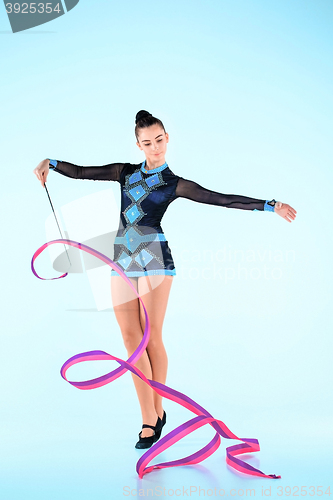 Image of The girl doing gymnastics dance with colored ribbon on a blue background