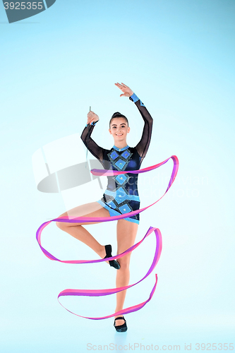 Image of The girl doing gymnastics dance with colored ribbon on a blue background