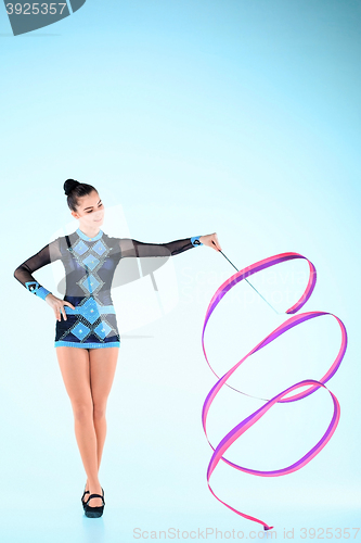 Image of The girl doing gymnastics dance with colored ribbon on a blue background