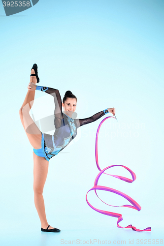 Image of The girl doing gymnastics dance with colored ribbon on a blue background