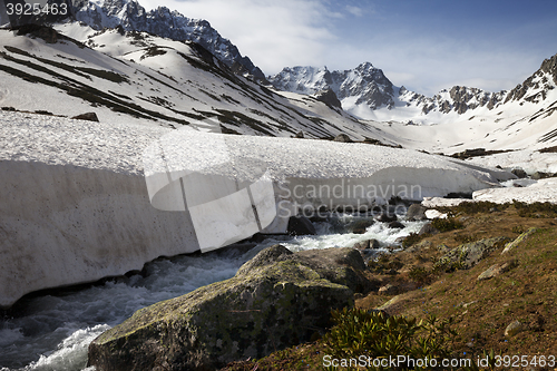 Image of River with snow bridges in spring mountains at sun day