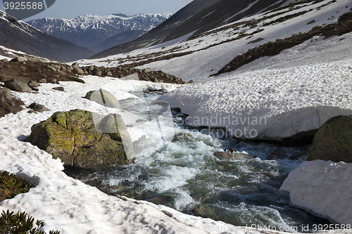 Image of River with snow bridges in spring mountains at sun day