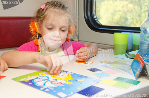 Image of A small child in a train of fun playing at the table at the lower place in the second-class compartment wagon