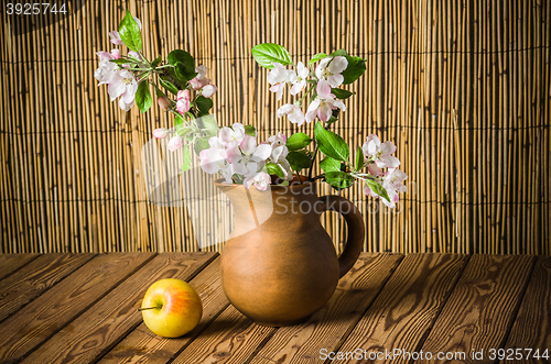 Image of Ripe apple and blossoming branch of an apple-tree in a clay jar,