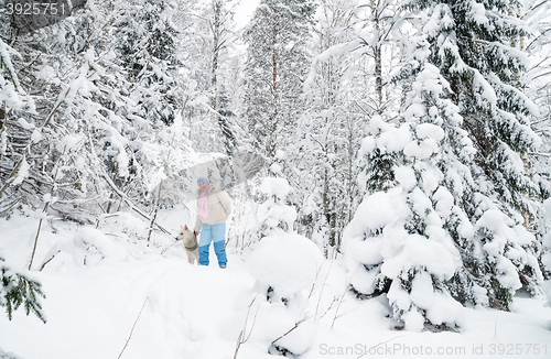 Image of The woman with a dog on walk in a winter wood