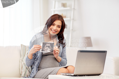 Image of happy pregnant woman with ultrasound image at home