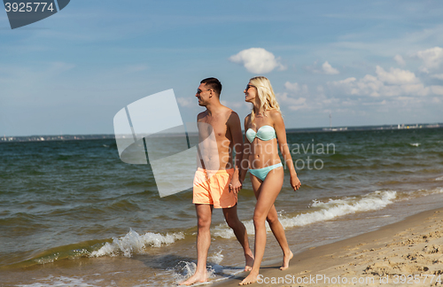 Image of happy couple in swimwear walking on summer beach