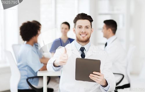 Image of happy doctor with tablet pc over team at clinic