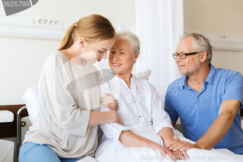 Image of happy family visiting senior woman at hospital