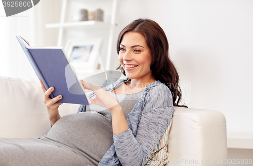 Image of happy pregnant woman reading book at home