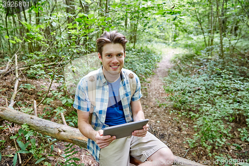 Image of happy man with backpack and tablet pc in woods