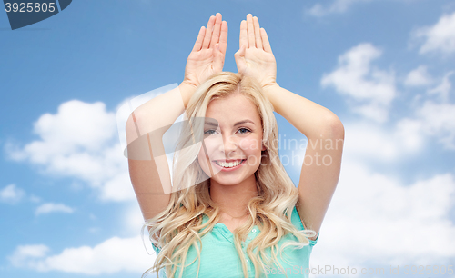 Image of happy smiling young woman making bunny ears